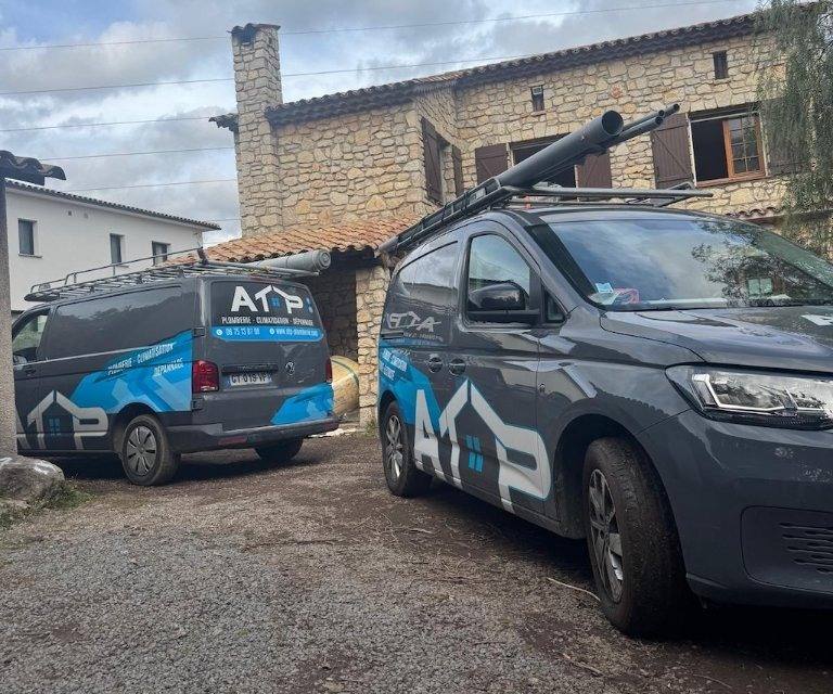 Deux utilitaires ATP Plomberie devant une maison en pierre en chantier
